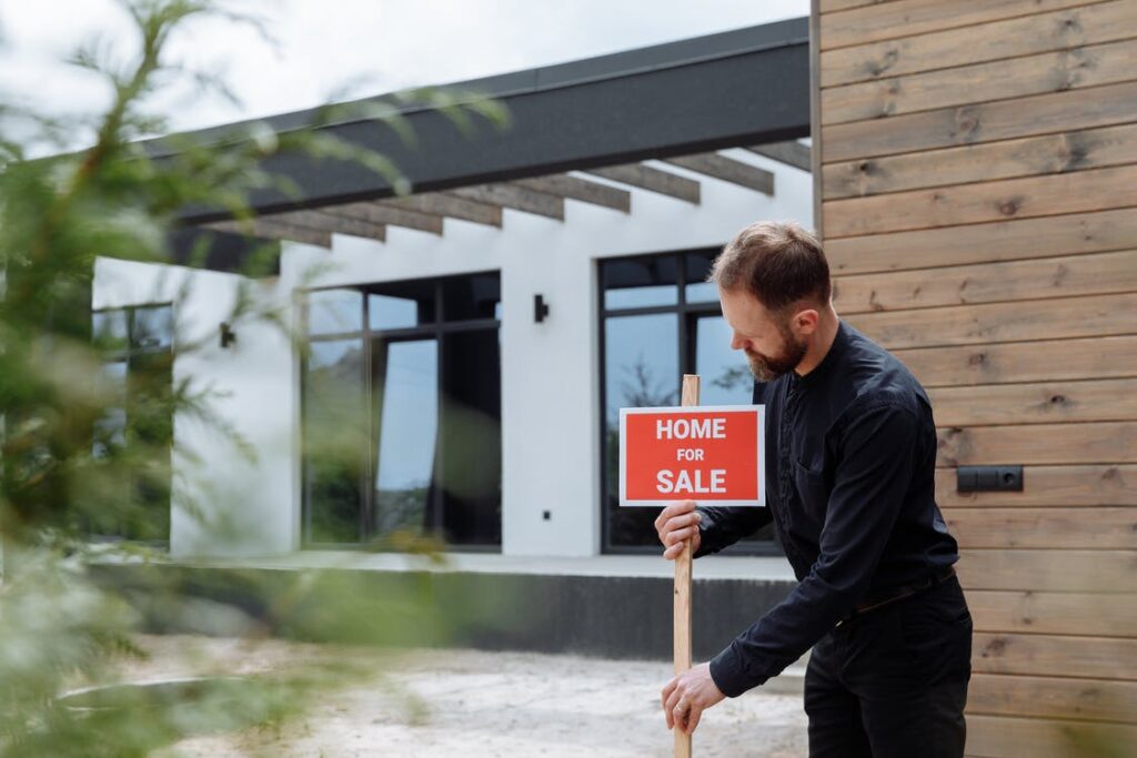 Man putting a Home for Sale sign